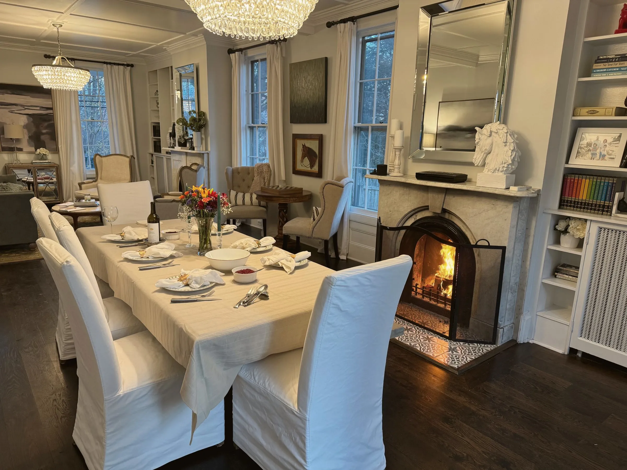 The dining table set for dinner, fire lit in the marble fireplace