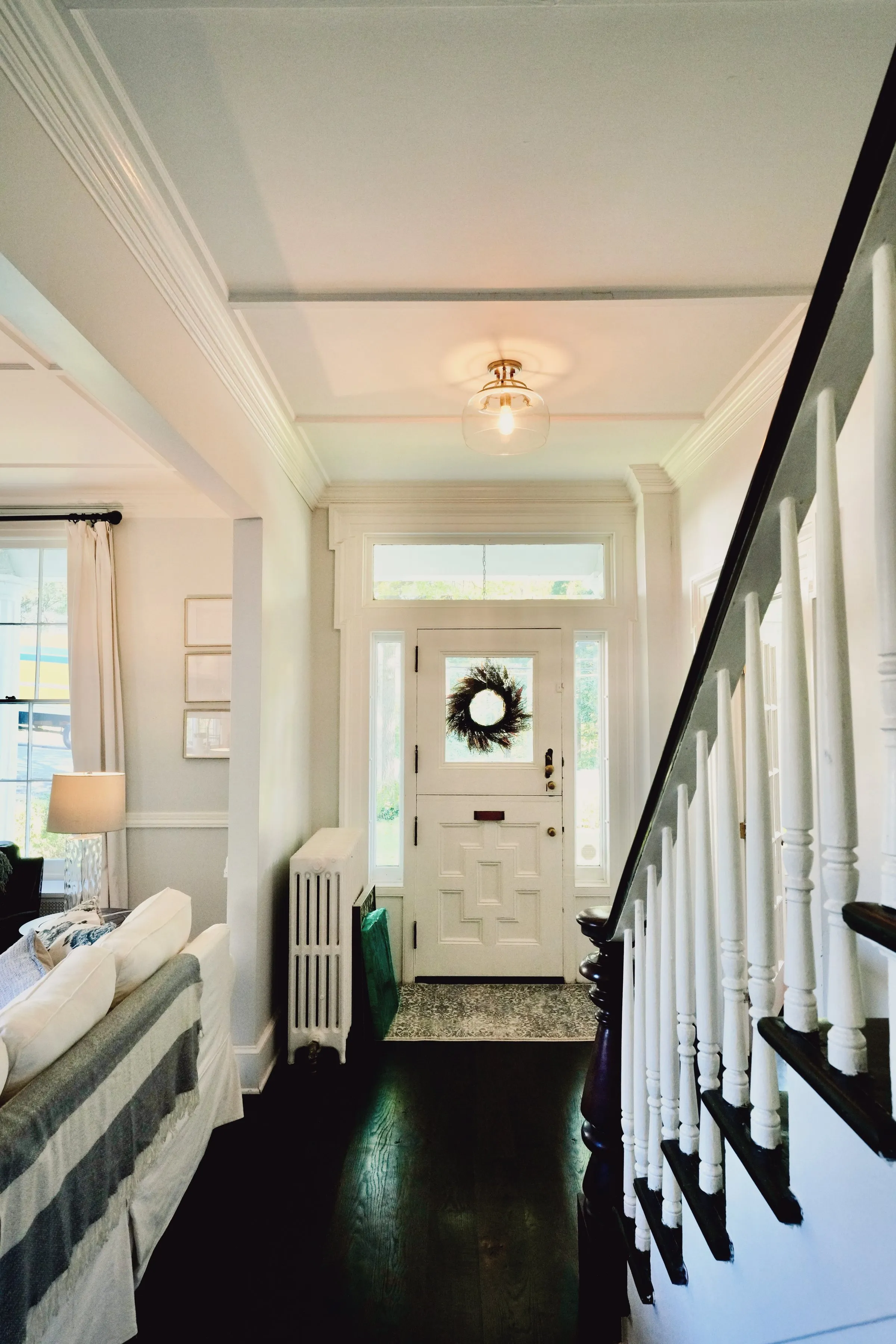 The entry hall — the original staircase, the front door with its wreath